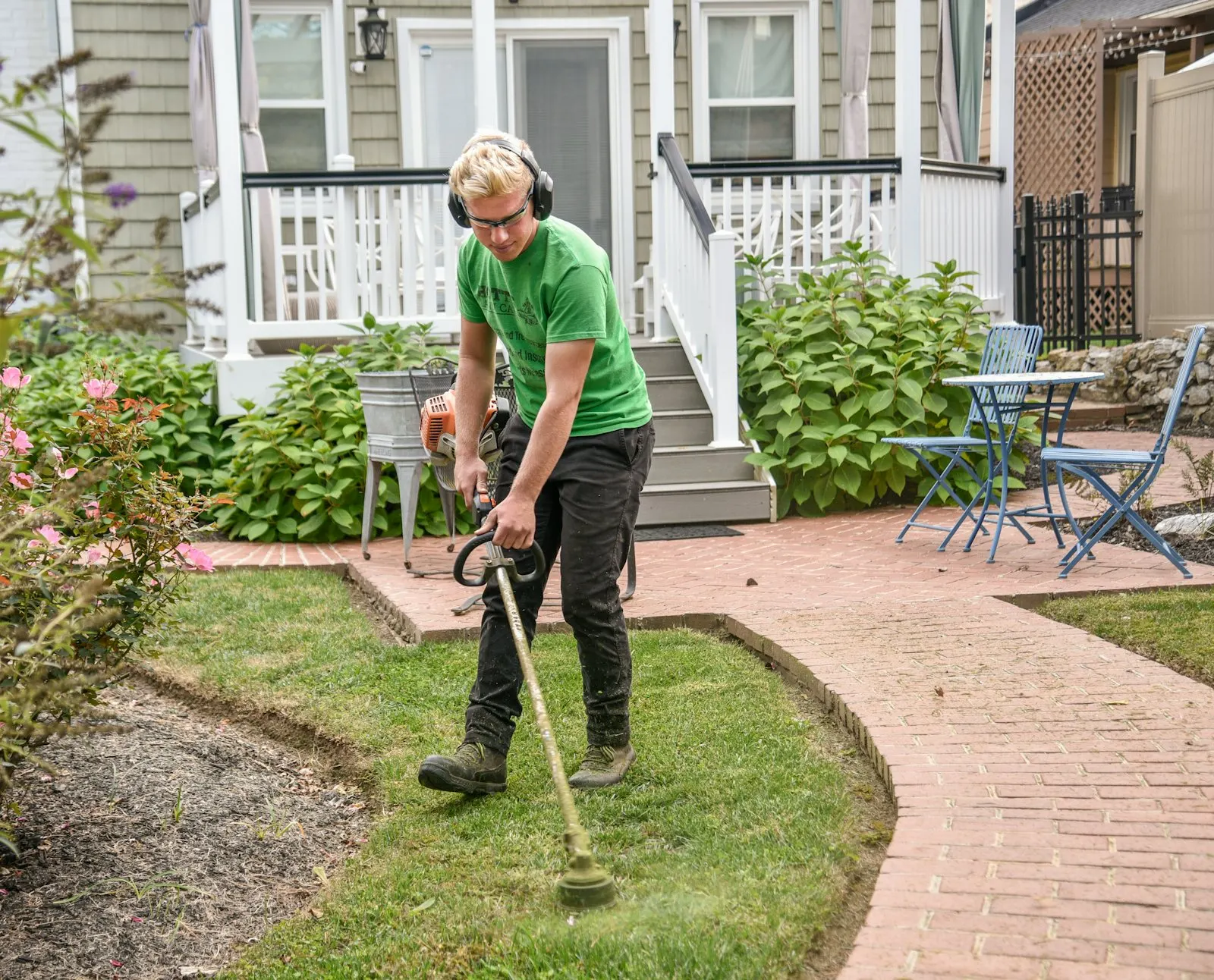 String trimmer cutting a clean line along a residential sidewalk.